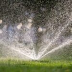 plastic sprinkler irrigating grass lawn with water gtfu9nd